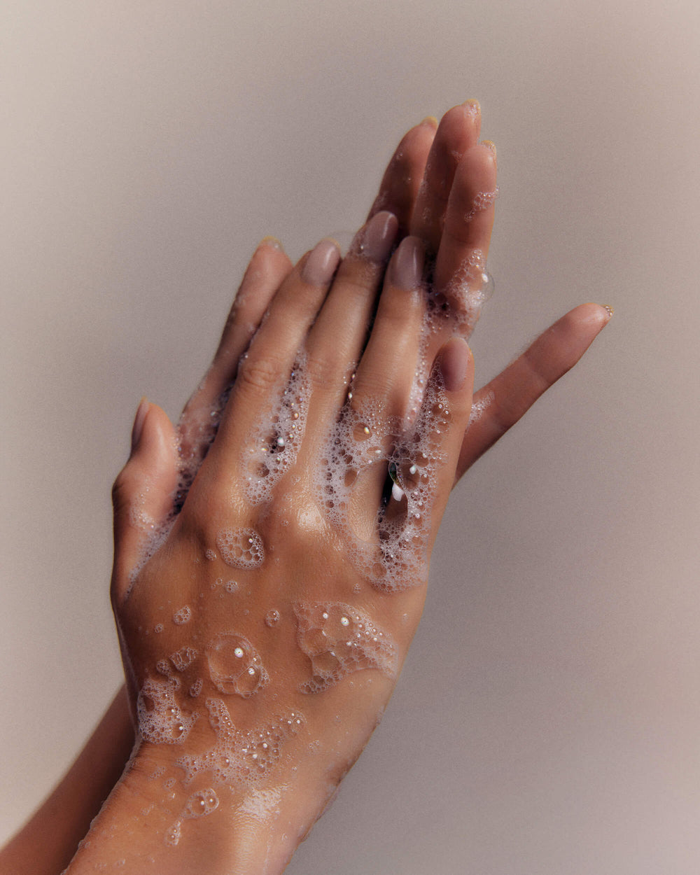Hands covered in foamy soap rub together, cleaning.