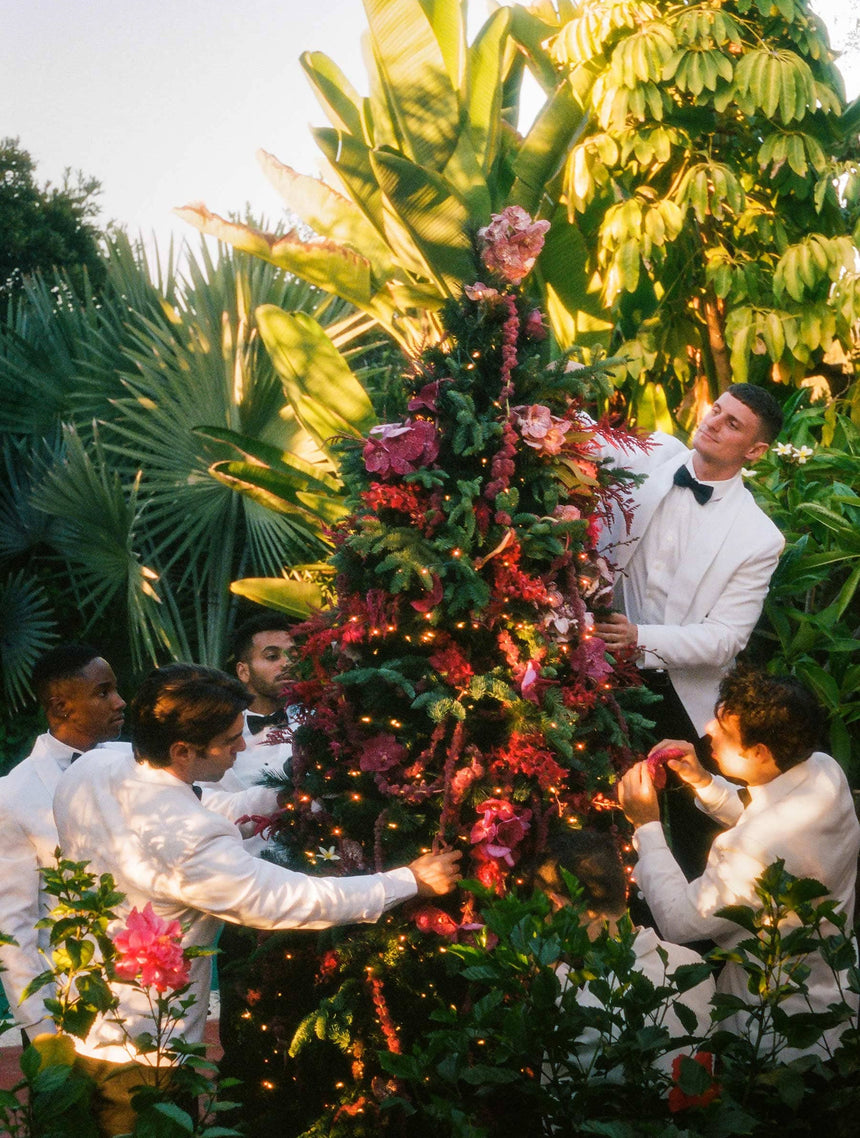 Men In White Suits Decorating A Christmas Tree