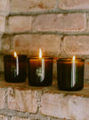 Three Lit Candles On A Brick Wall